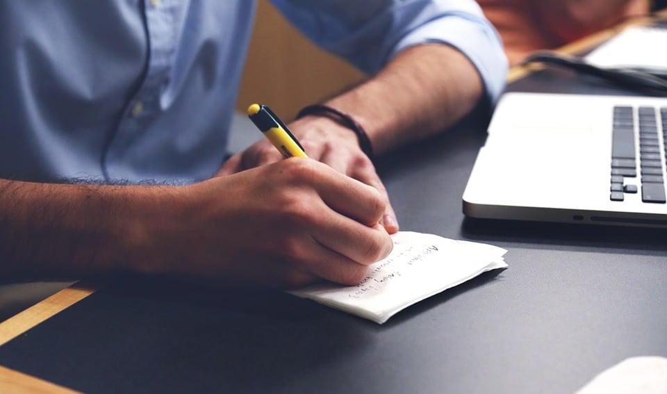 In an office environment, a man in a suit is diligently taking notes at his desk