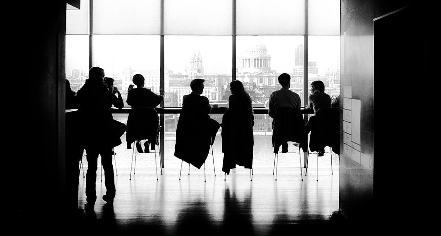 A group of coworkers is depicted in a black and white picture in the office.