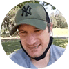 Client smiling in outdoor setting wearing green cap